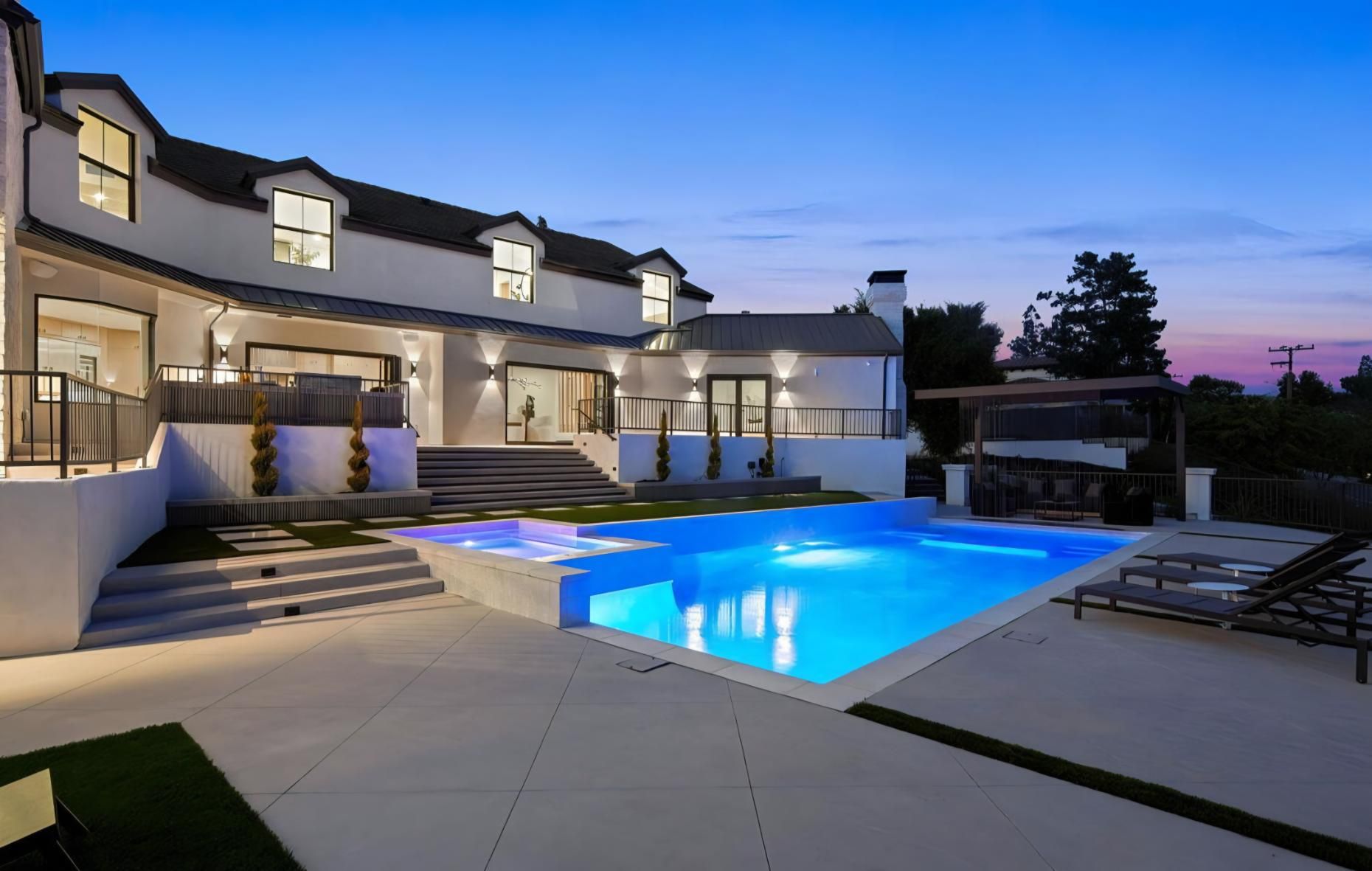 Luxury modern home with lit pool at dusk