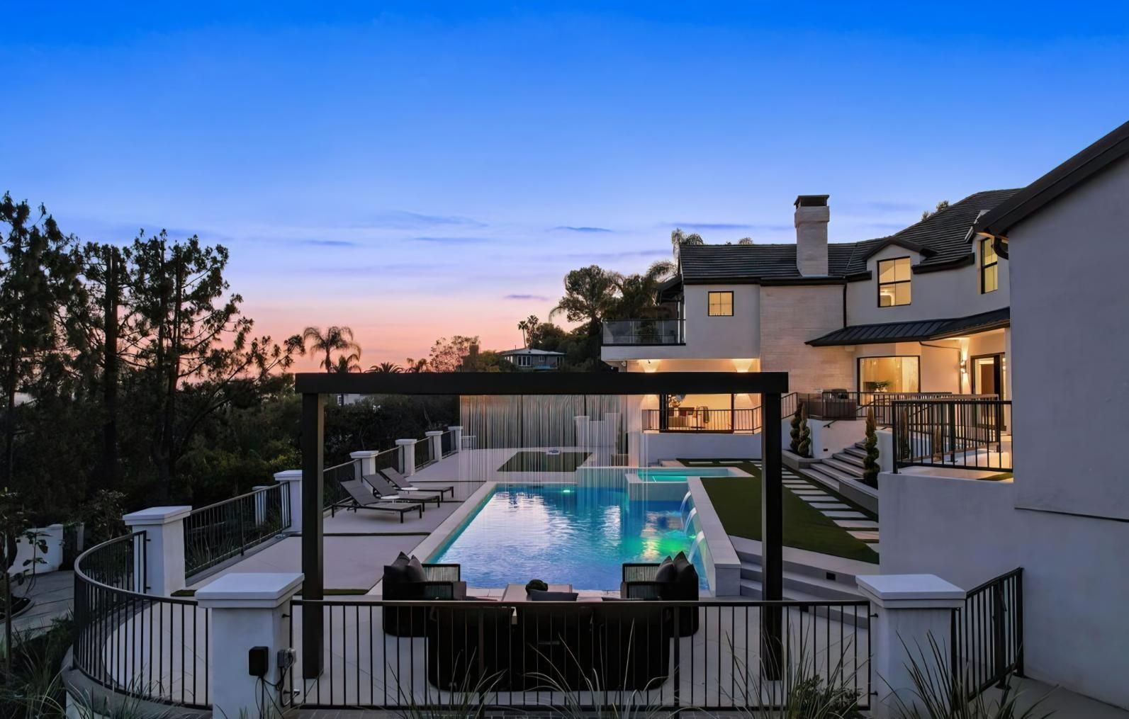 Modern house patio with lit swimming pool at dusk and a mountain view