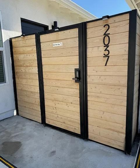 Wooden and black modern gate with house number 2037 on a concrete driveway