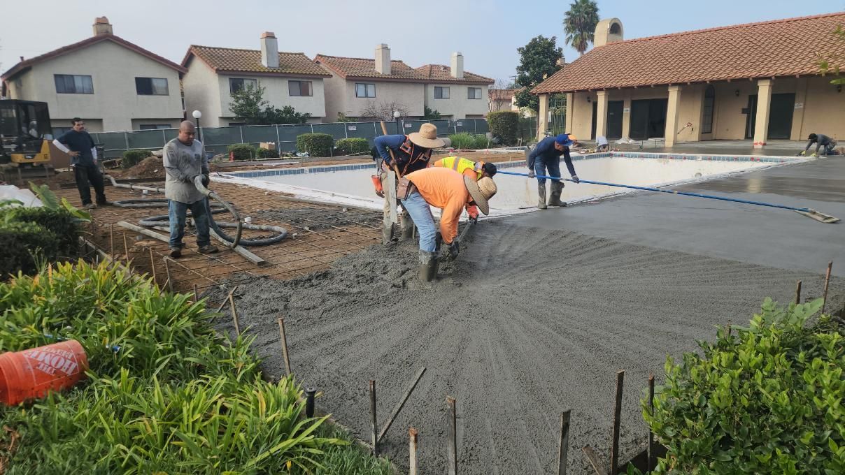 Workers pouring fresh concrete for a driveway at a residential construction site
