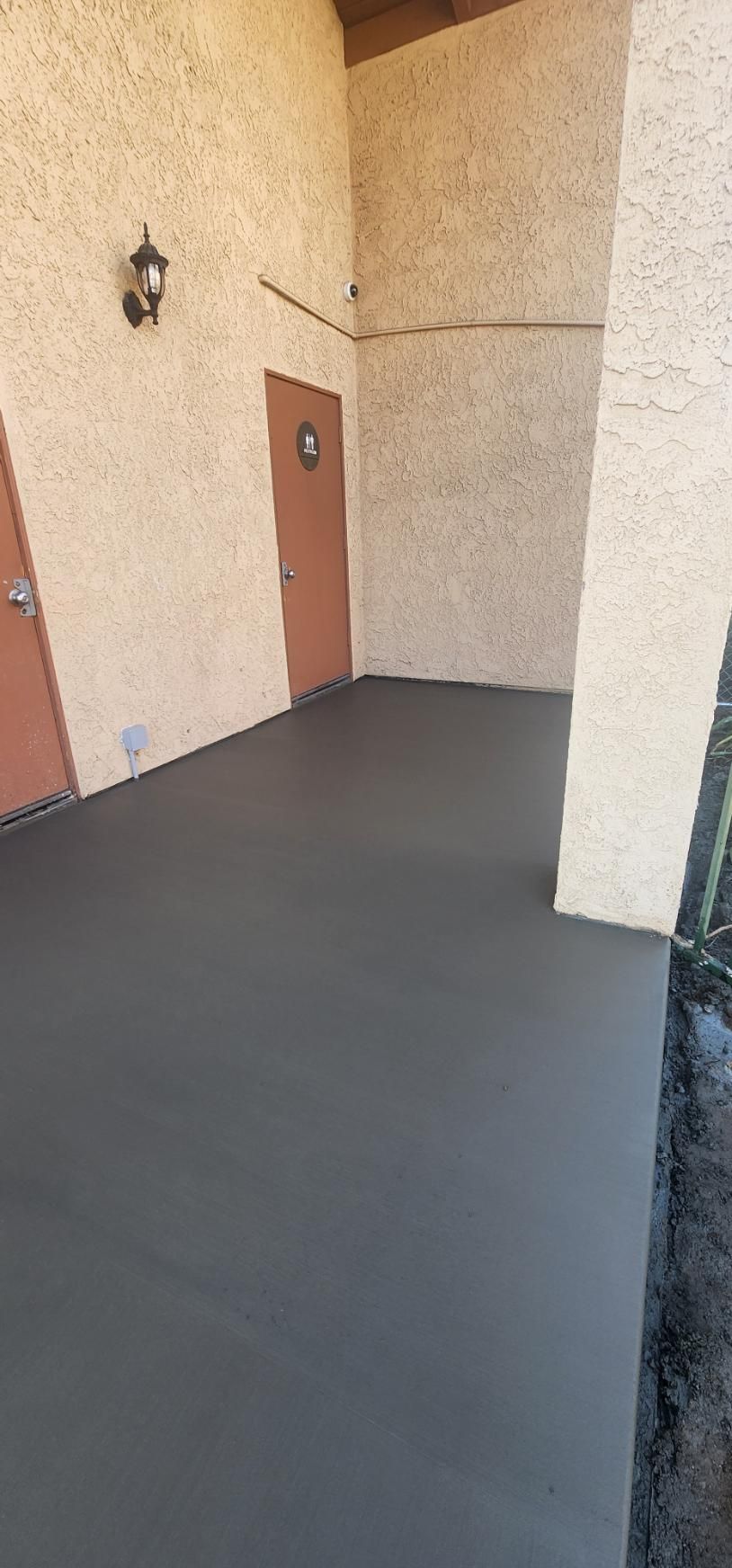 Empty apartment entryway with beige walls, brown doors, and dark gray flooring.