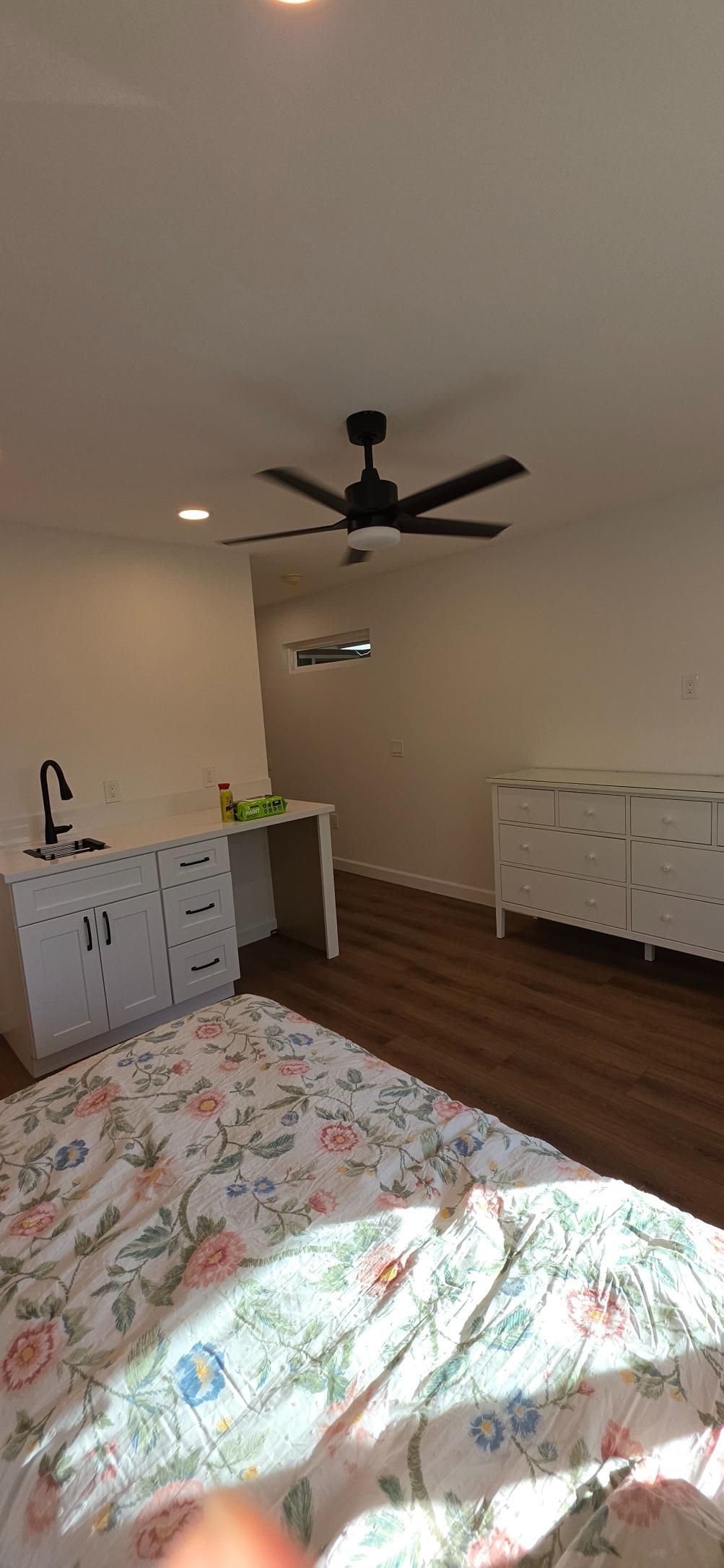 Sunlit bedroom with bed, dresser, ceiling fan, and hardwood floor