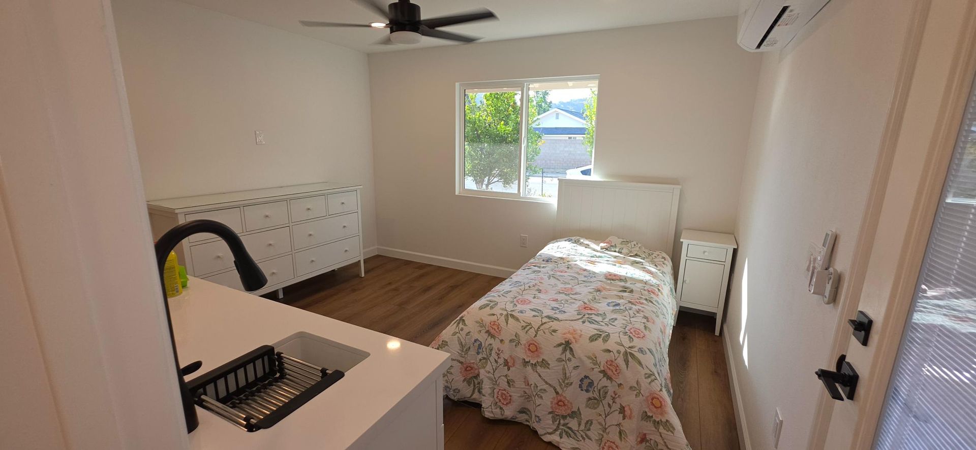 Bright bedroom with a bed, desk, ceiling fan, and window