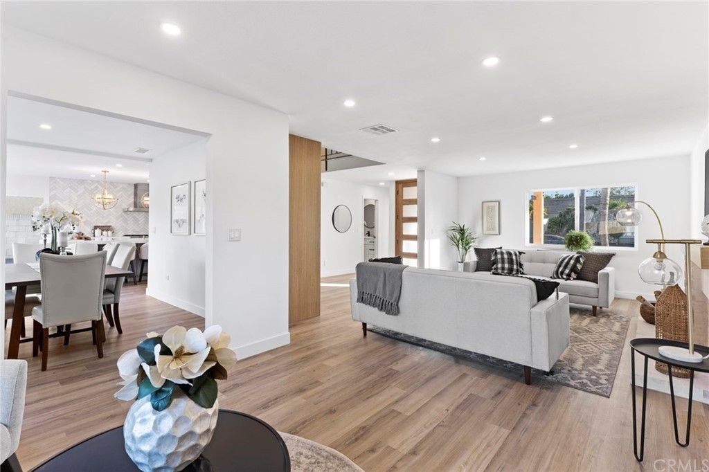 Bright open-plan living room and dining area with white walls, wood floors, and modern furnishings