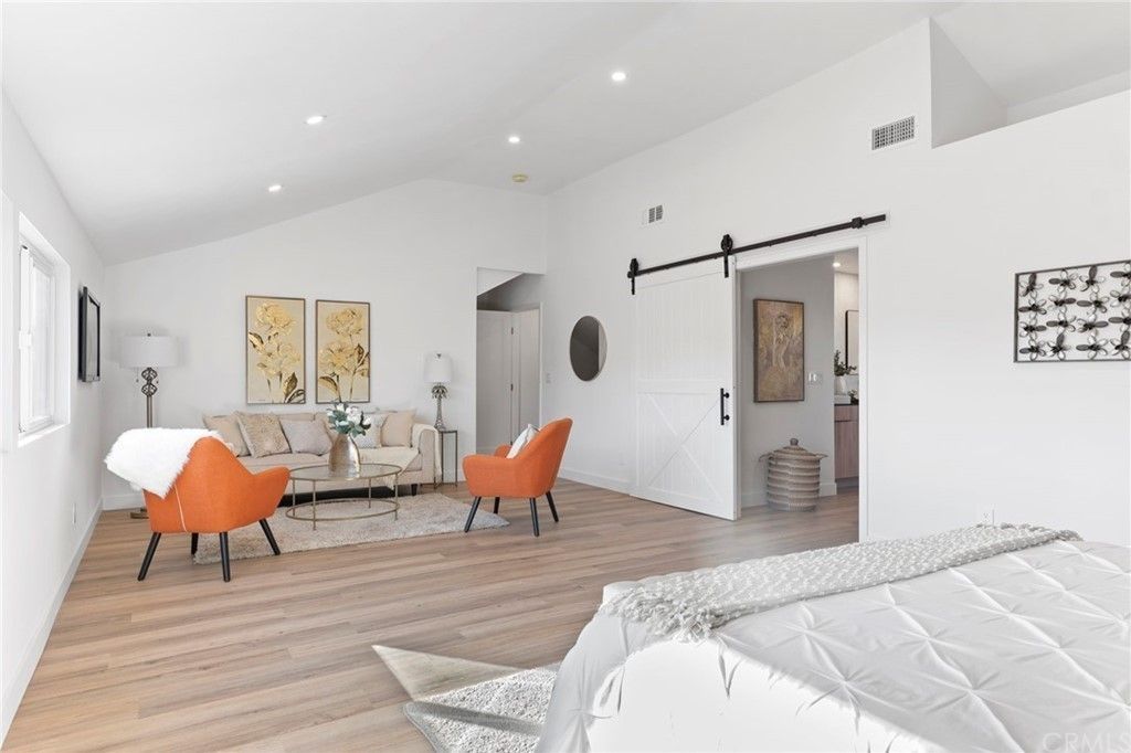 Bright modern bedroom with orange chairs, a desk, and barn-style sliding door