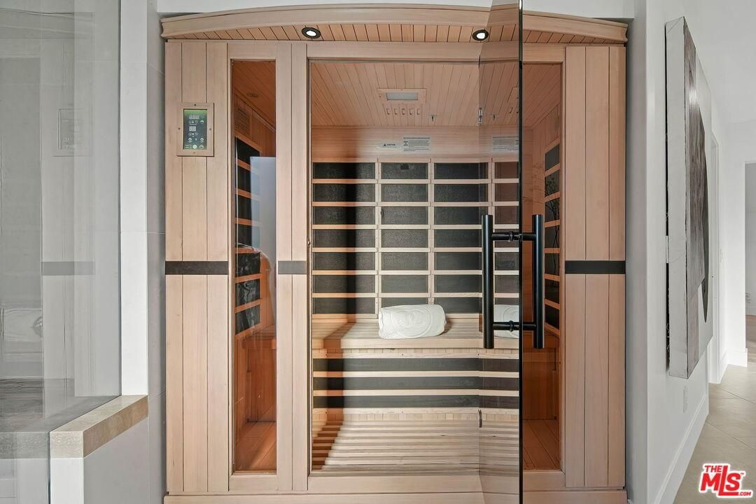 Wooden sauna or steam room with glass door, bench seating, and white towels inside