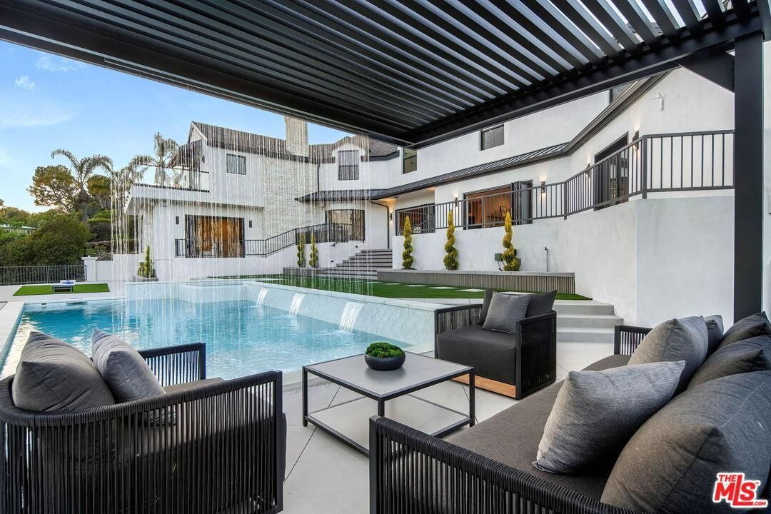 Modern backyard pool patio with black lounge seating and white contemporary house