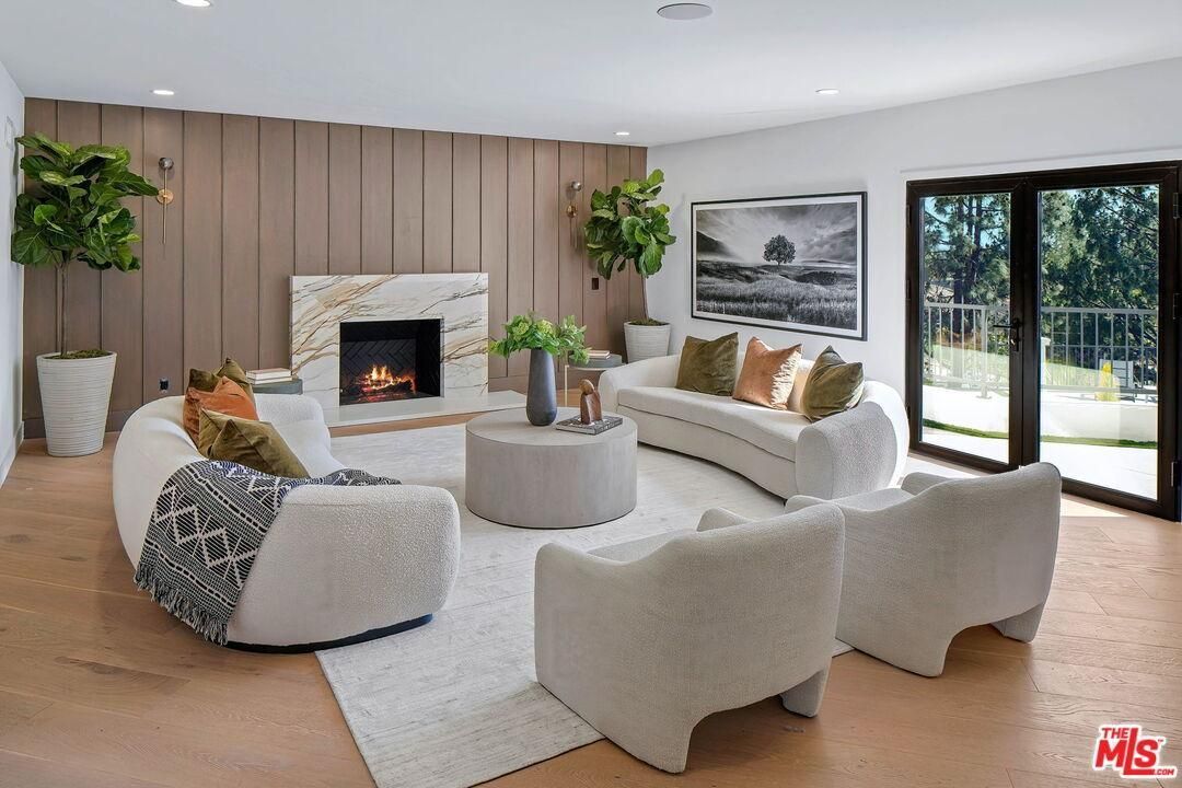 Bright modern living room with white sofas, fireplace, and large sliding glass doors
