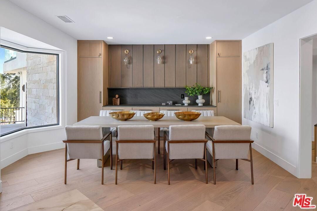 Modern dining room with a long table, six chairs, and wood cabinets beneath skylights