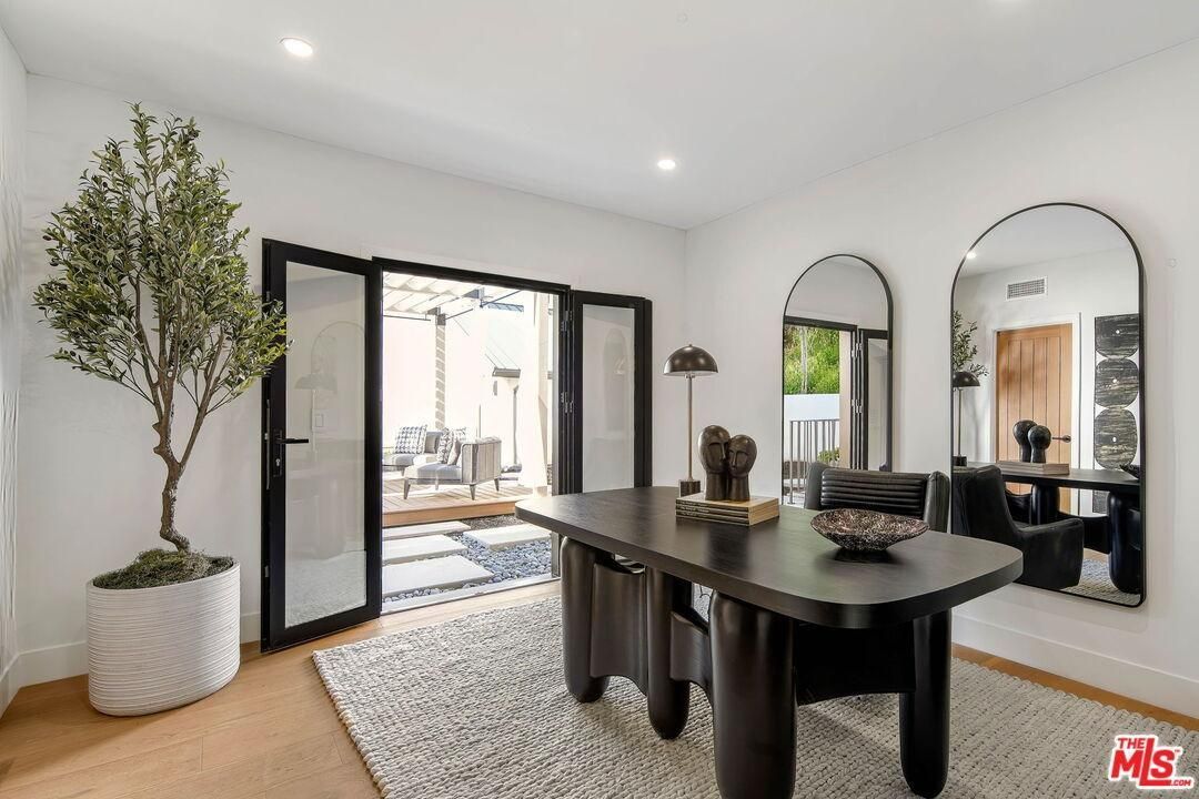 Bright dining room with a black table, arched mirrors, and open doors to a patio.