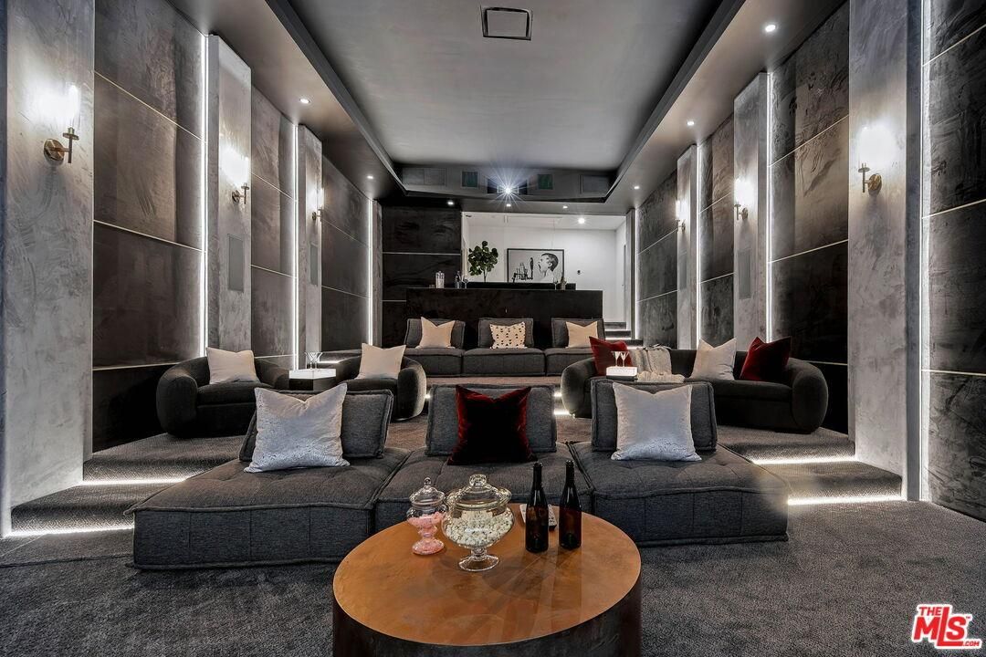 Modern luxury lounge with dark walls, recessed lighting, plush seating, and a round coffee table