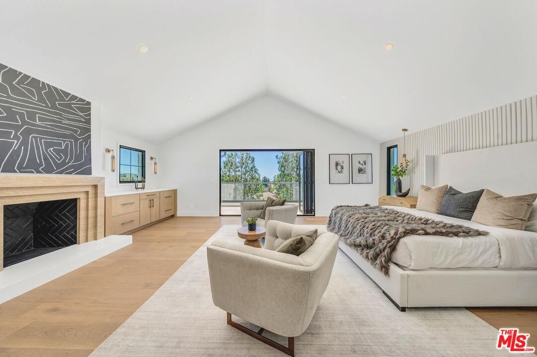 Bright living room with vaulted ceiling, fireplace, beige sectional, and large sliding glass doors overlooking trees