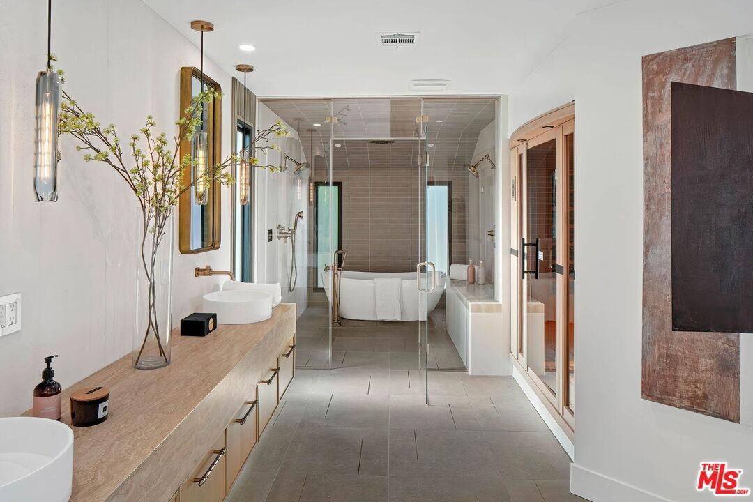 Bright modern hallway with console table, wall art, pendant lights, and a bathroom at the end.
