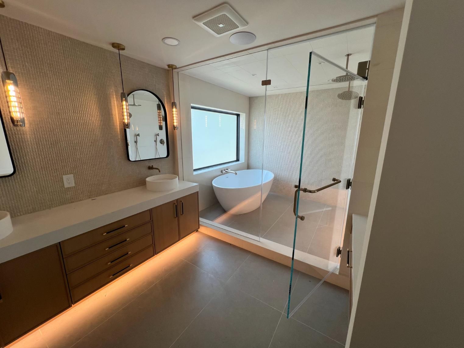 Modern bathroom with freestanding tub, glass shower, wood vanity, and patterned tile walls