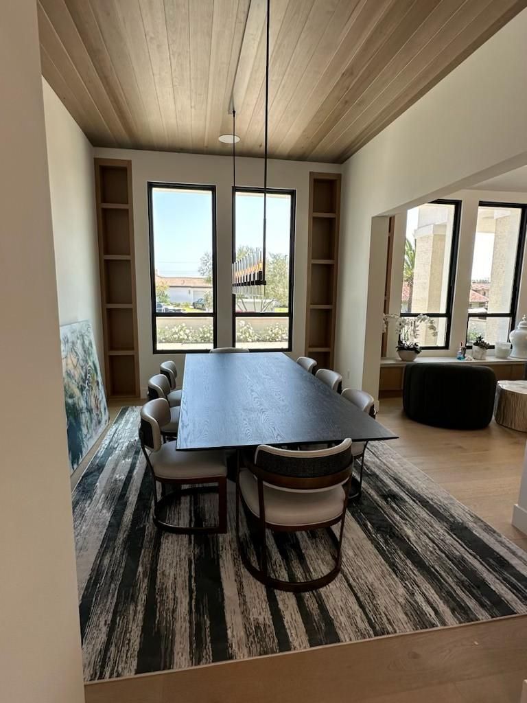 Modern dining room with a long dark table, mixed chairs, and large glass doors leading outside