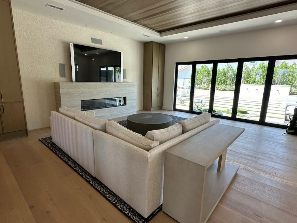 Modern living room with beige sectional, fireplace, TV, and large glass doors opening to a patio.