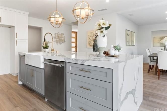 Bright modern kitchen with white cabinets, marble island, and gold pendant lights