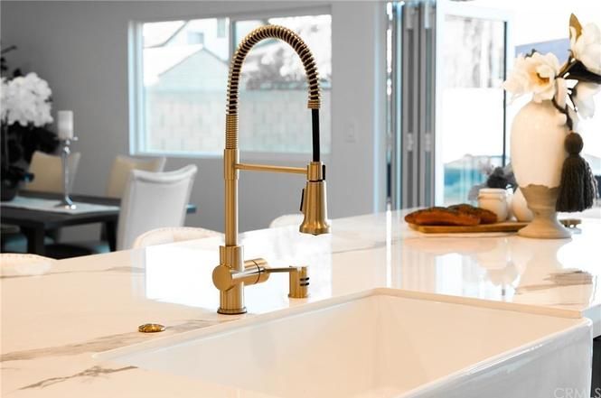 Modern kitchen sink with gold faucet and white marble countertop in a bright room