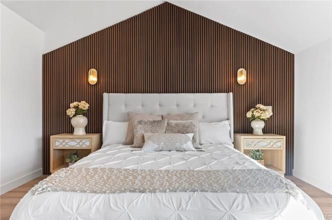 Bright bedroom with a tufted bed, wood slat accent wall, and matching bedside lamps and flowers