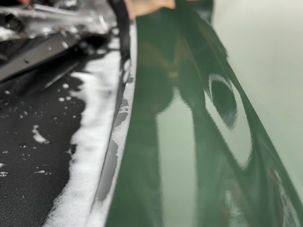 Green car door being washed with soapy water.