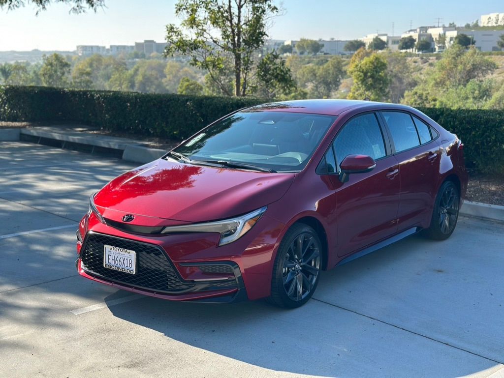 Red Toyota Corolla sedan parked on pavement.