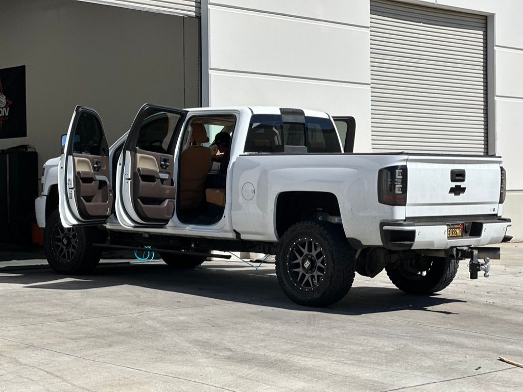 White pickup truck with doors open, parked in front of a building.