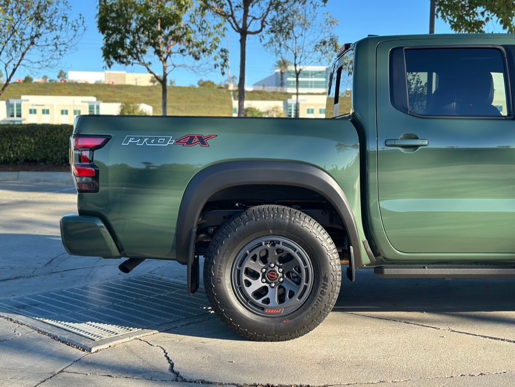 Green Nissan Frontier pickup truck; black fender flares and wheels; sunny outdoors.