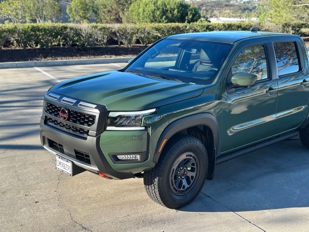Green Nissan Frontier pickup truck parked outdoors.