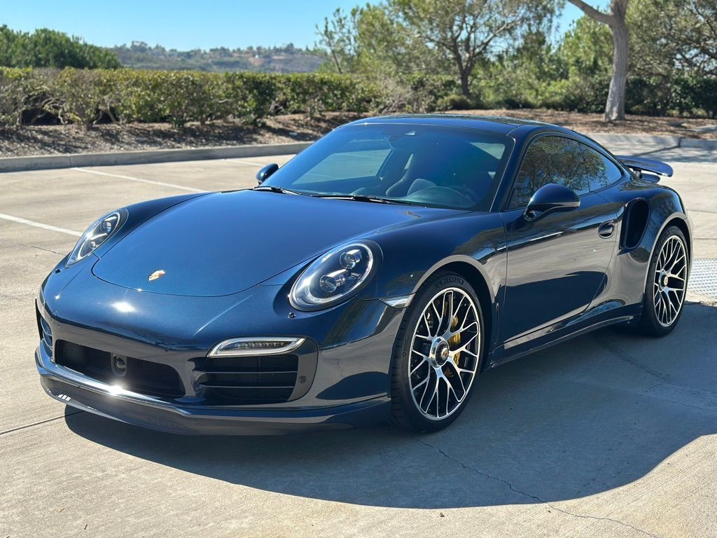 Blue Porsche sports car parked on asphalt, sunny day.
