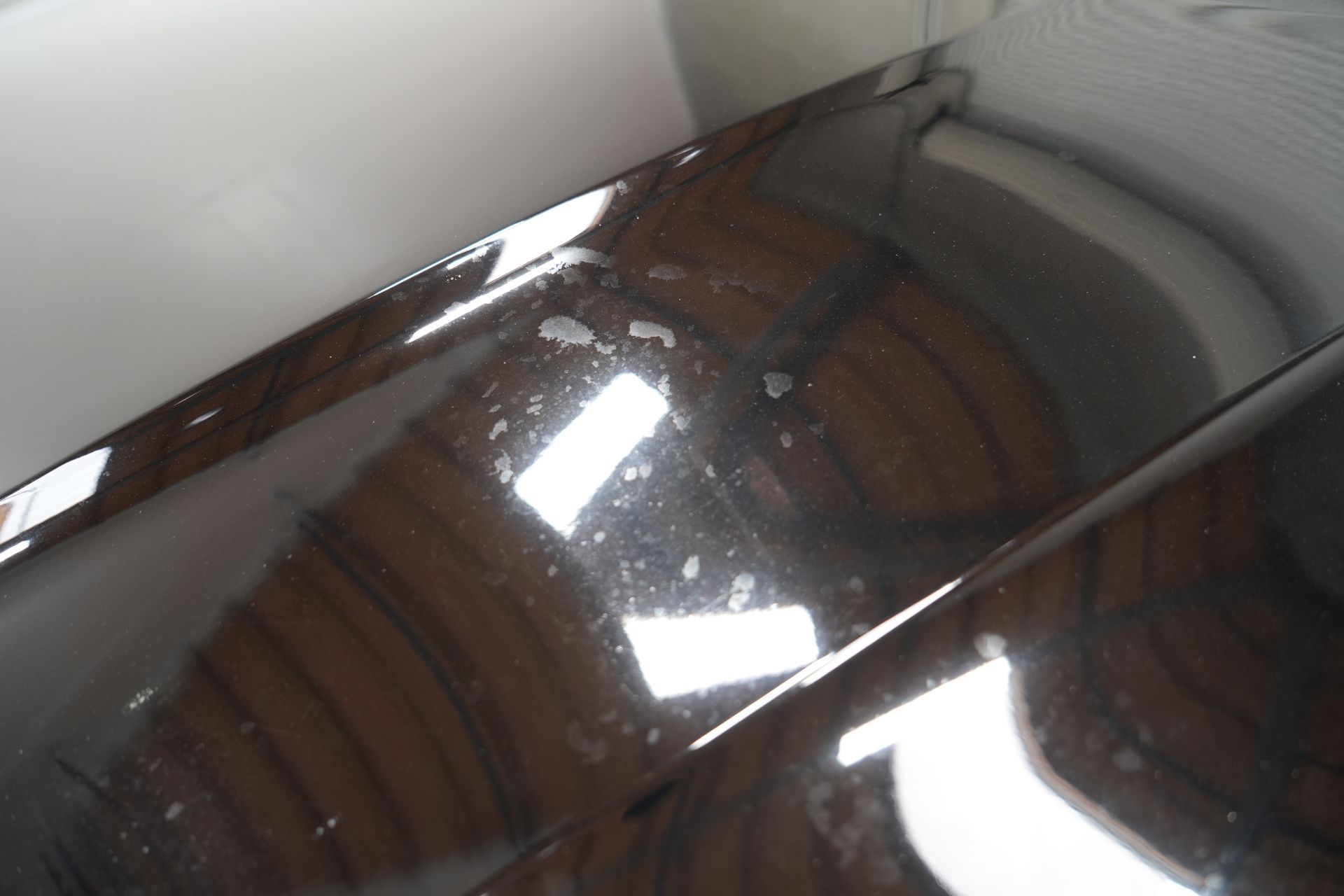A shiny metal surface with a reflection of a wooden ceiling