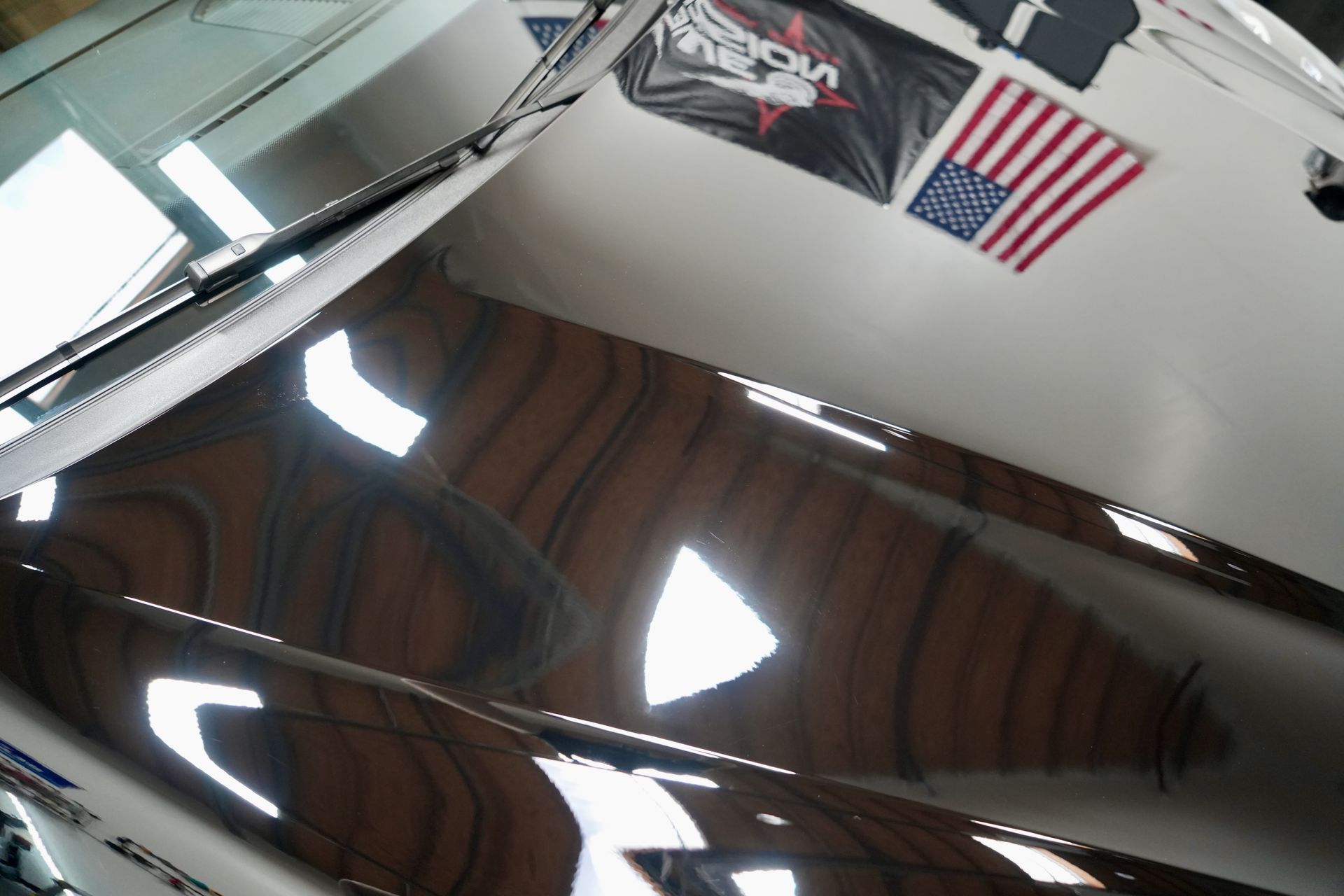 A close up of a car hood in a garage with american flags on the wall