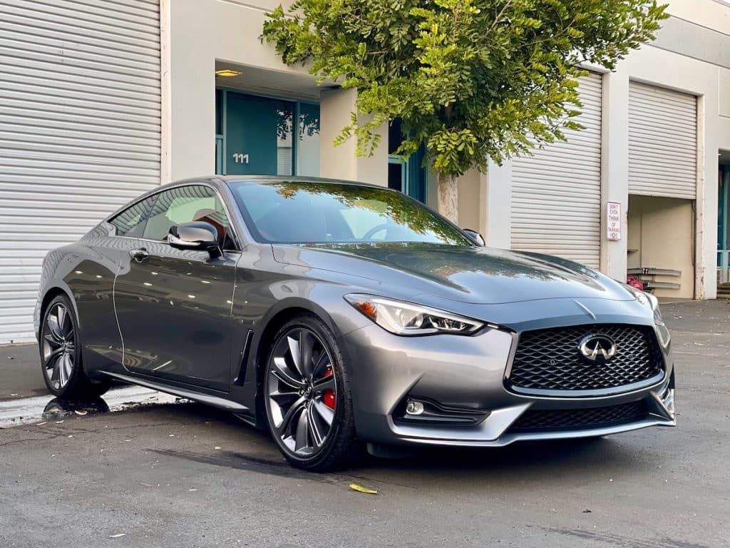 A gray infiniti q50 coupe is parked in front of a building.