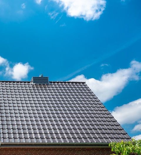 Gray tiled roof under a bright blue sky with white clouds