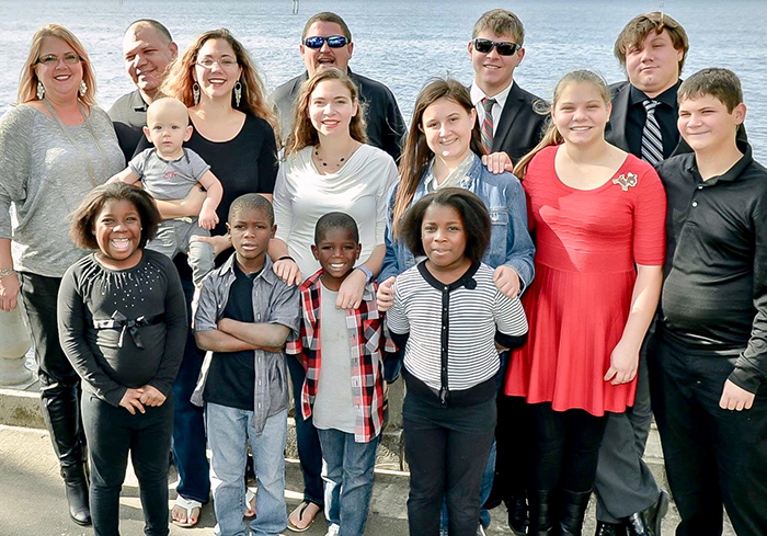A large group of people standing together outdoors, smiling at the camera.