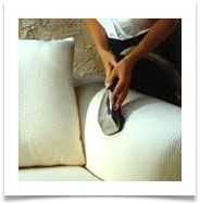Person using a handheld vacuum to clean a white couch cushion