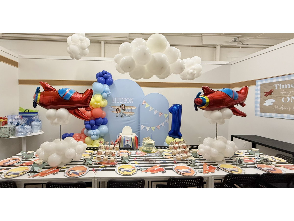 Colorful cartoon-themed birthday party table with balloons, clouds, and Spider-Man decorations