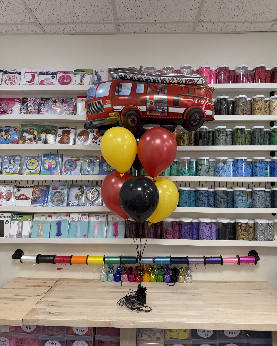 Halloween party display with fire truck balloon centerpiece, colorful balloons, and decorated dessert table