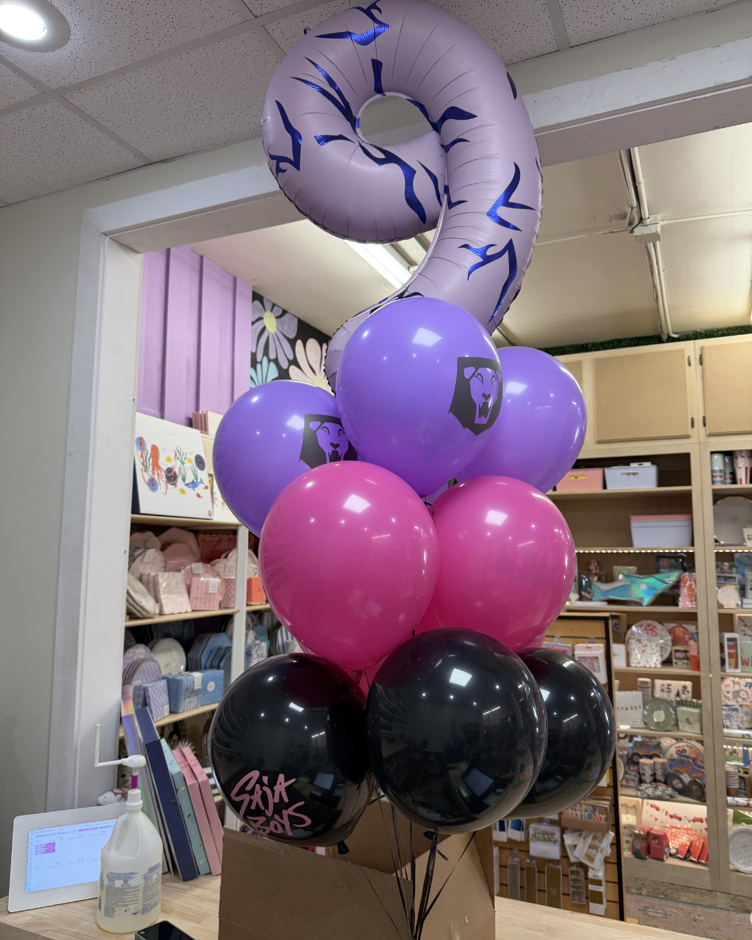 Balloon column in purple, pink, and black with a large lavender number 2 in a store interior