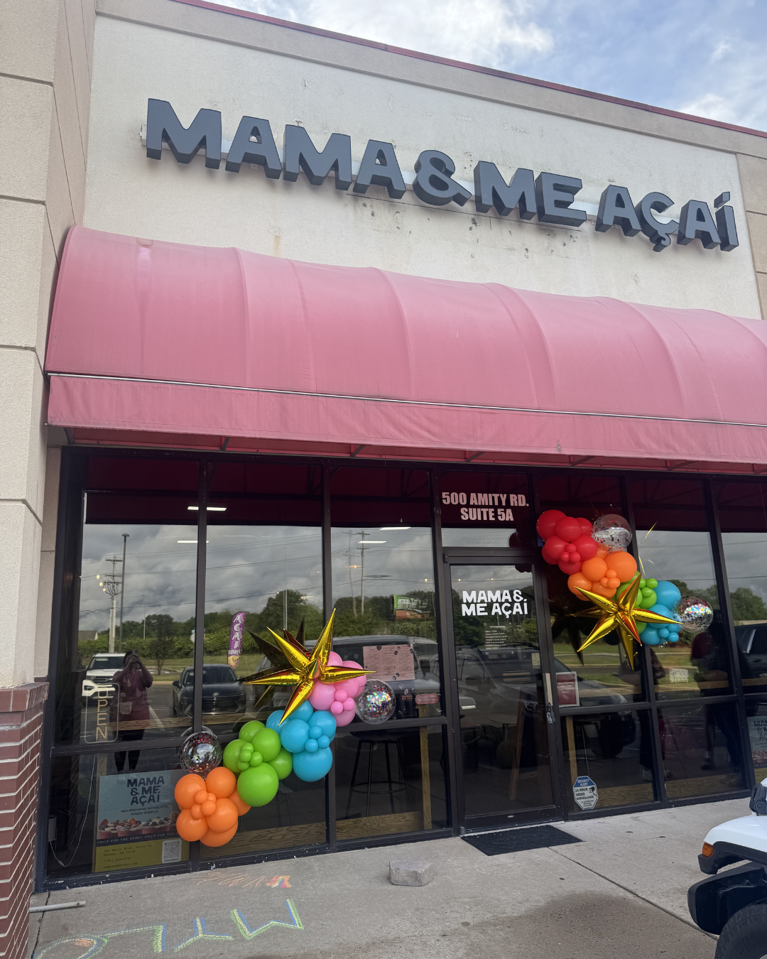 Mama & Me Academy storefront with pink awning and colorful balloon decorations by the entrance