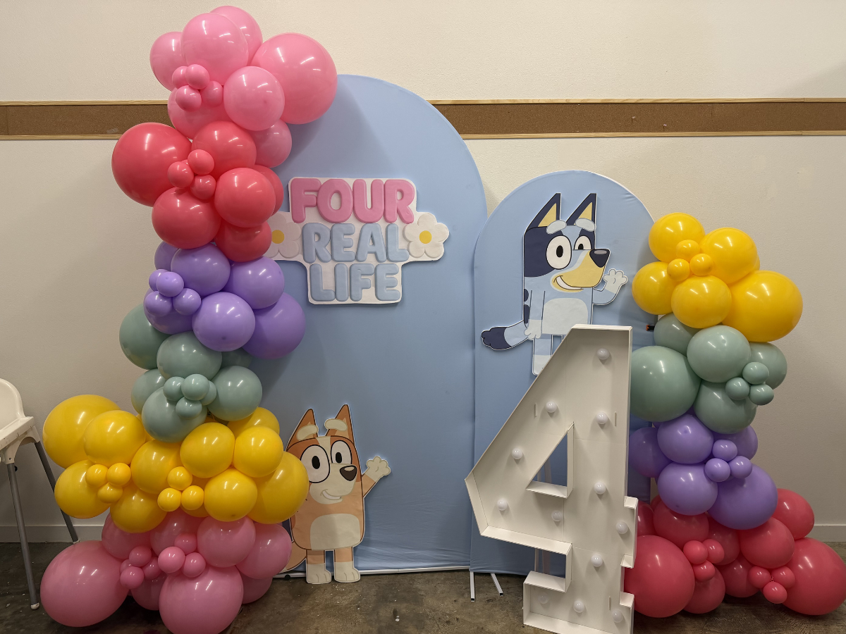 Bluey-themed party backdrop with colorful balloon columns and a large silver number 4
