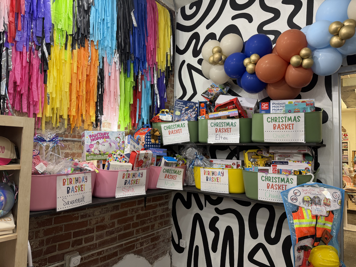 Colorful party treat display with balloon garland, streamers, and labeled snack boxes on shelves