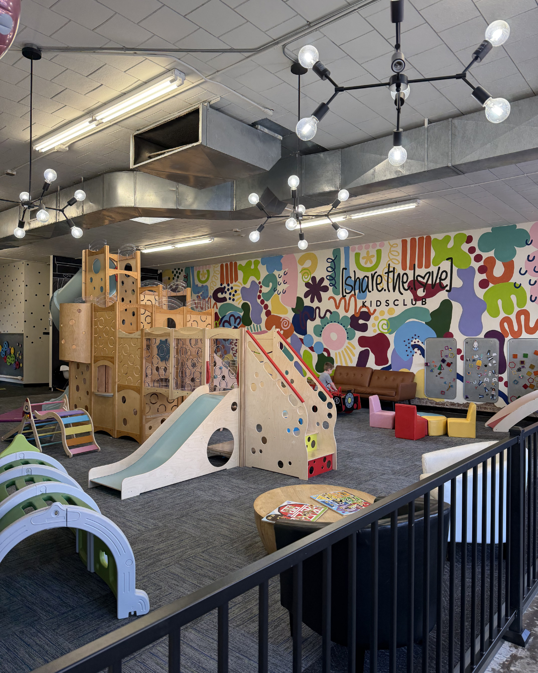 Indoor children's play area with slides, climbing structures, and colorful wall art