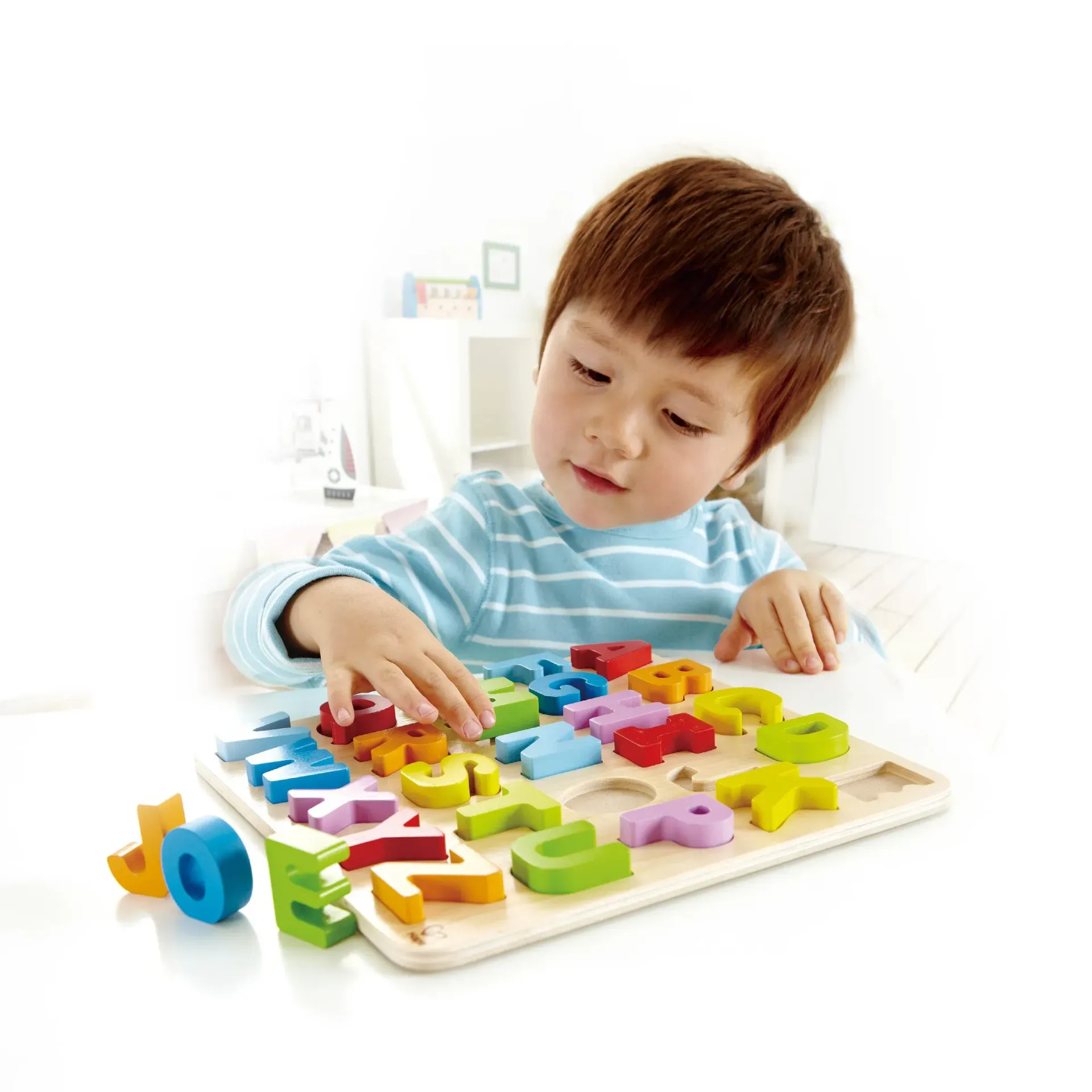 Child playing with colorful alphabet puzzle blocks on a table, concentrating with a slight smile