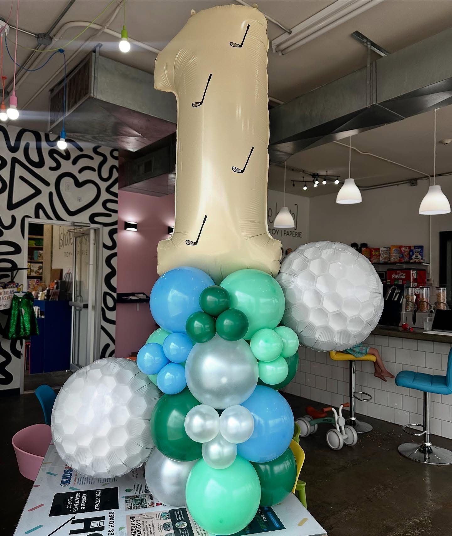 Number 1 balloon centerpiece with teal, blue, silver and white balloons in a shop