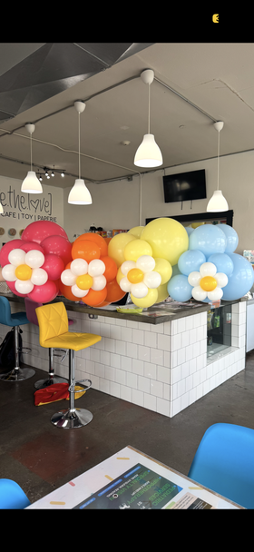 Colorful balloon flower arrangements at a decorated bar counter in a modern indoor venue