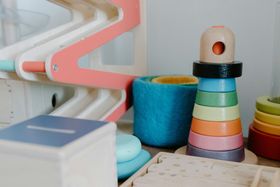 Colorful stacking toys and blocks on a shelf, including a pastel ring tower and blue cylinder.