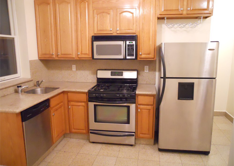 Kitchen with stainless steel appliances, wood cabinets, and a beige countertop.