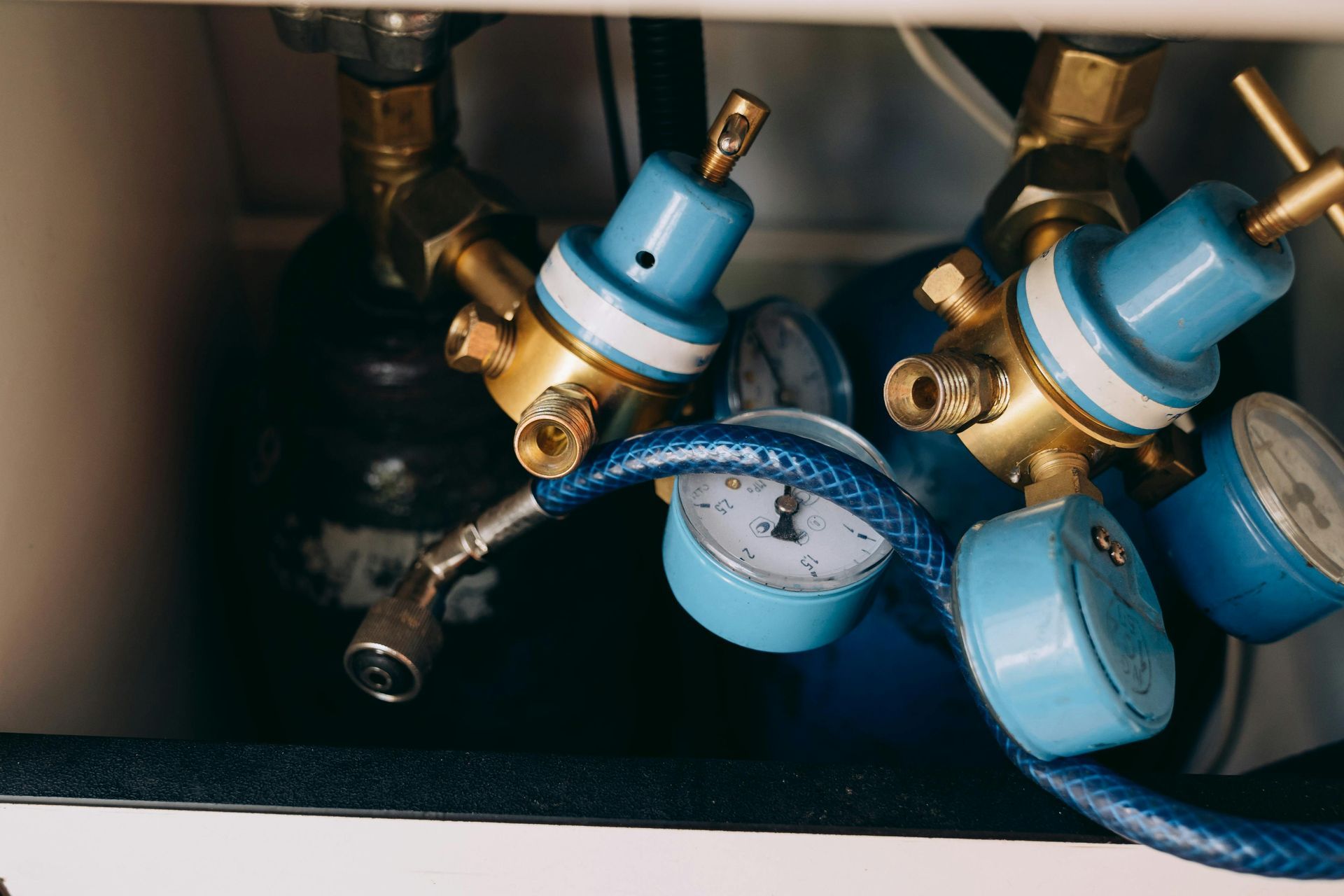 Blue and brass gas regulators connected to cylinders; medical or industrial equipment.