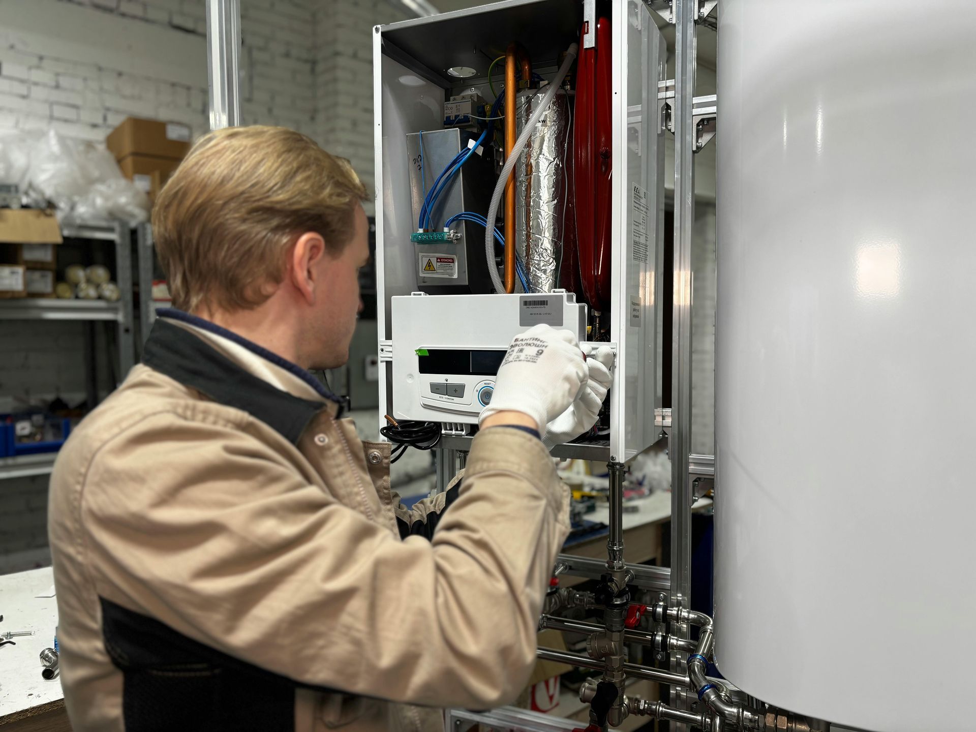 Technician in a lab adjusting equipment inside an open white industrial cabinet