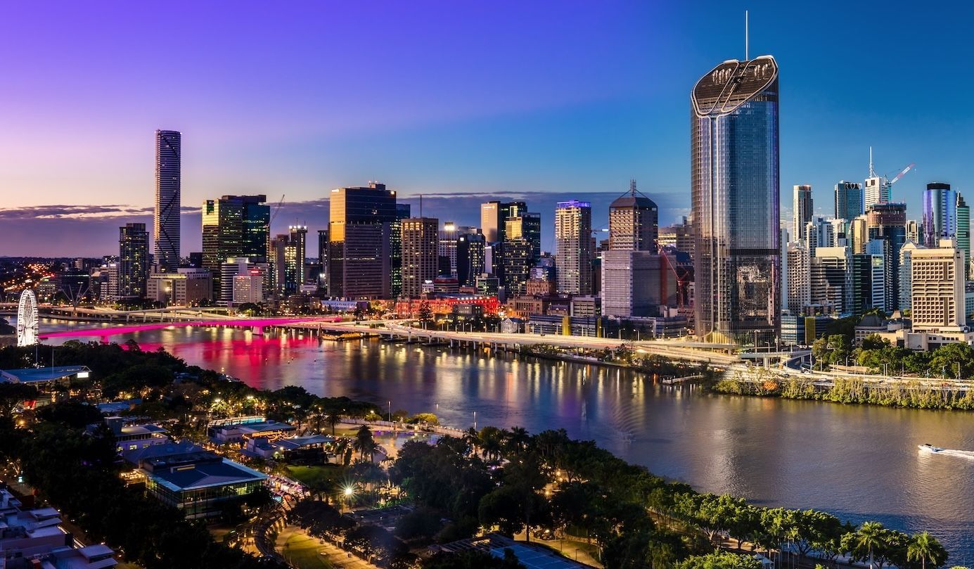 City skyline at dusk over a river, with colorful lights reflecting on the water— Couples Counseling in Brisbane, QLD